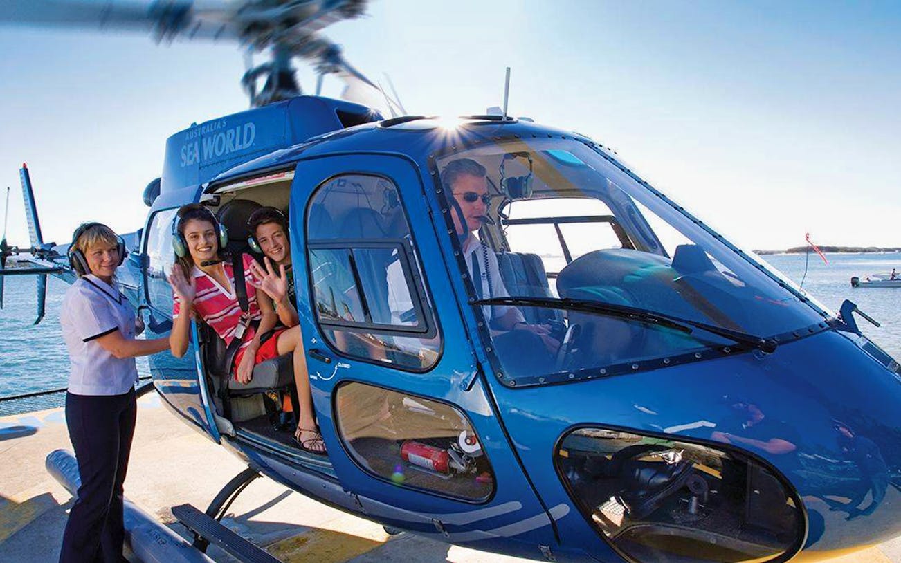 Helicopter on helipad with passengers preparing for Sea World scenic flight.
