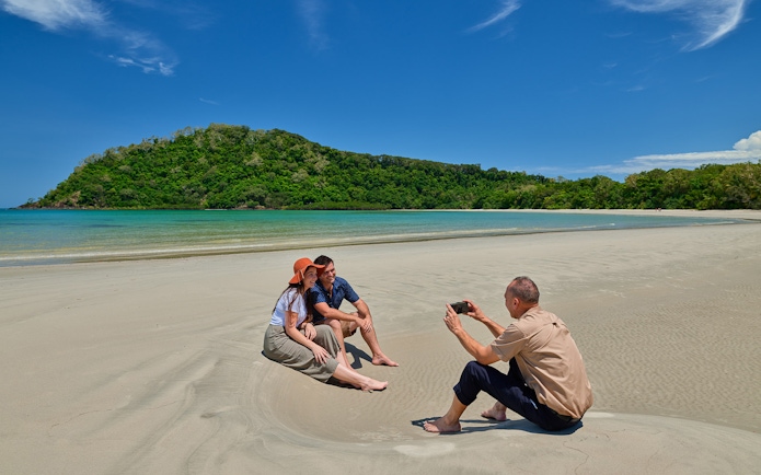 Couple posing for a photo on Cape Tribulation beach during guided tour, Daintree.