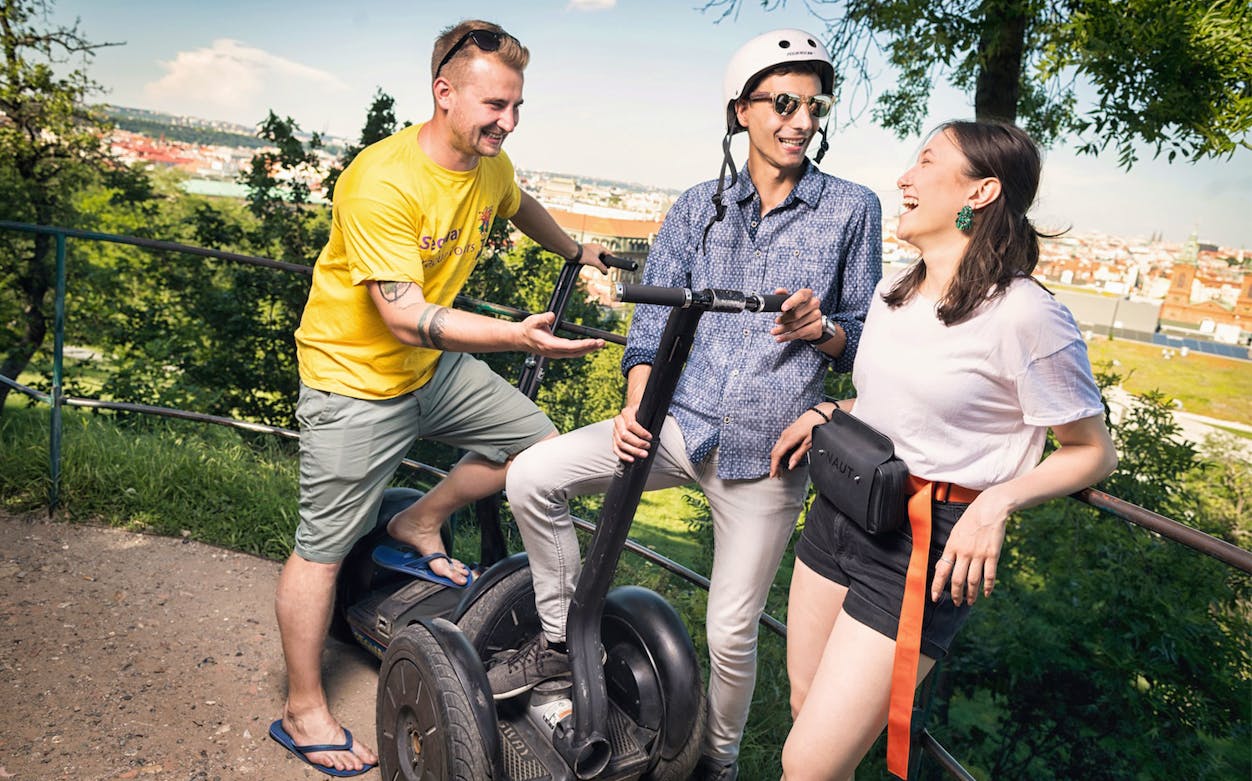 Group enjoying a Segway tour with a view of Prague in the background.