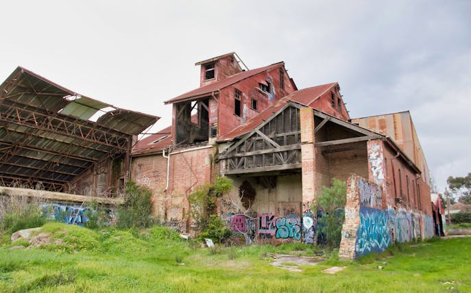 Abandoned red brick building with graffiti, part of Old Melbourne Ghost Tour.