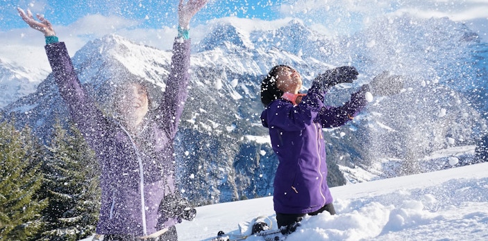 Snowshoers enjoying snow on Lombachalp guided tour with mountain backdrop.