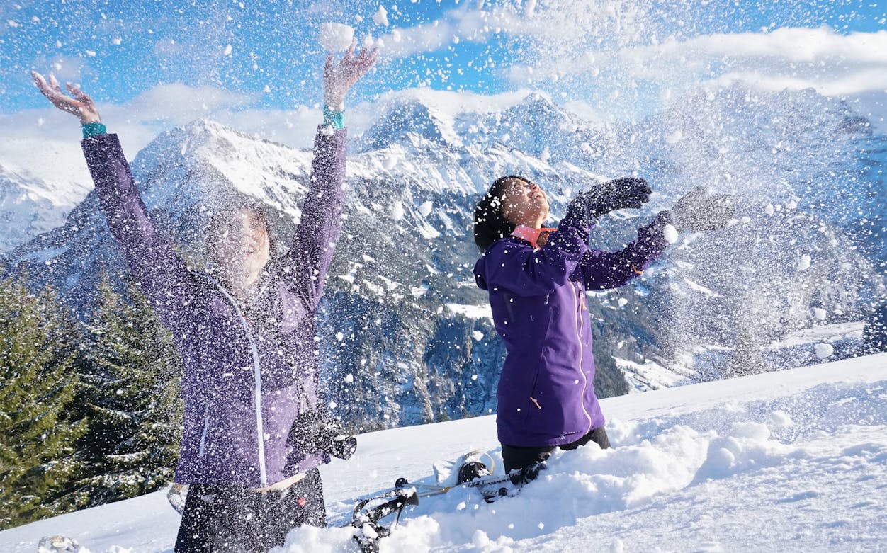 Snowshoers enjoying snow on Lombachalp guided tour with mountain backdrop.