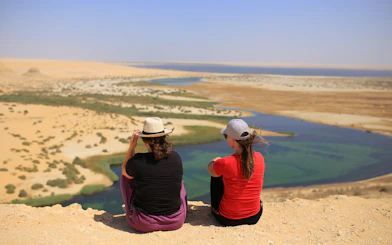 Two people overlooking desert landscape with oasis during 4x4 safari tour from Cairo.