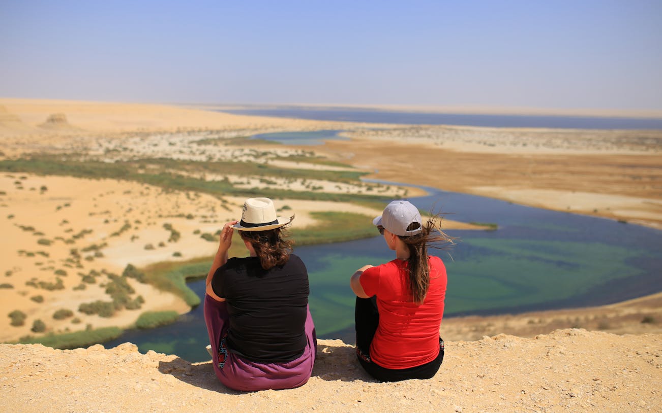 Two people overlooking desert landscape with oasis during 4x4 safari tour from Cairo.