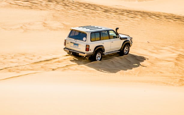 4x4 vehicle driving on sand dunes during a desert safari near Cairo.