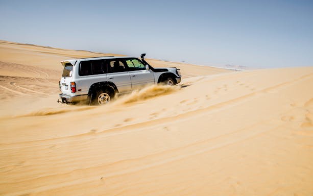 4x4 vehicle driving through desert dunes on a safari tour from Cairo.