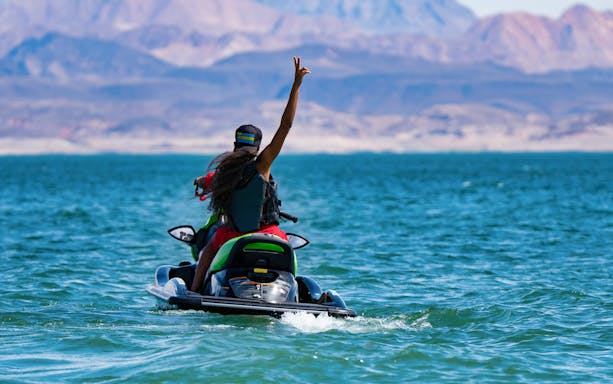 Person riding a jet ski on the Red Sea with mountains in the background.