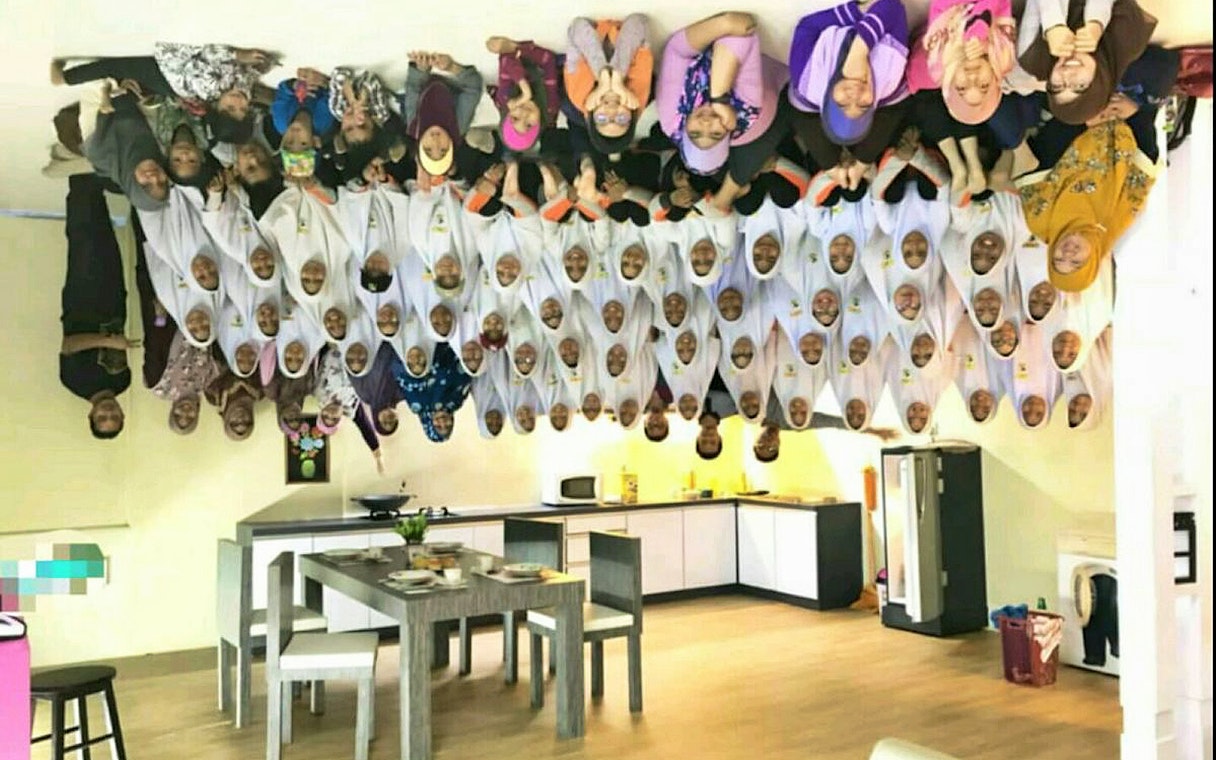 Group of people posing in an upside-down kitchen at Upside Down House Melaka.