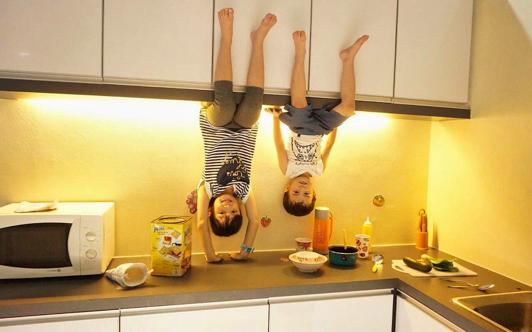 Children appearing upside down in a kitchen at Upside Down House Melaka.