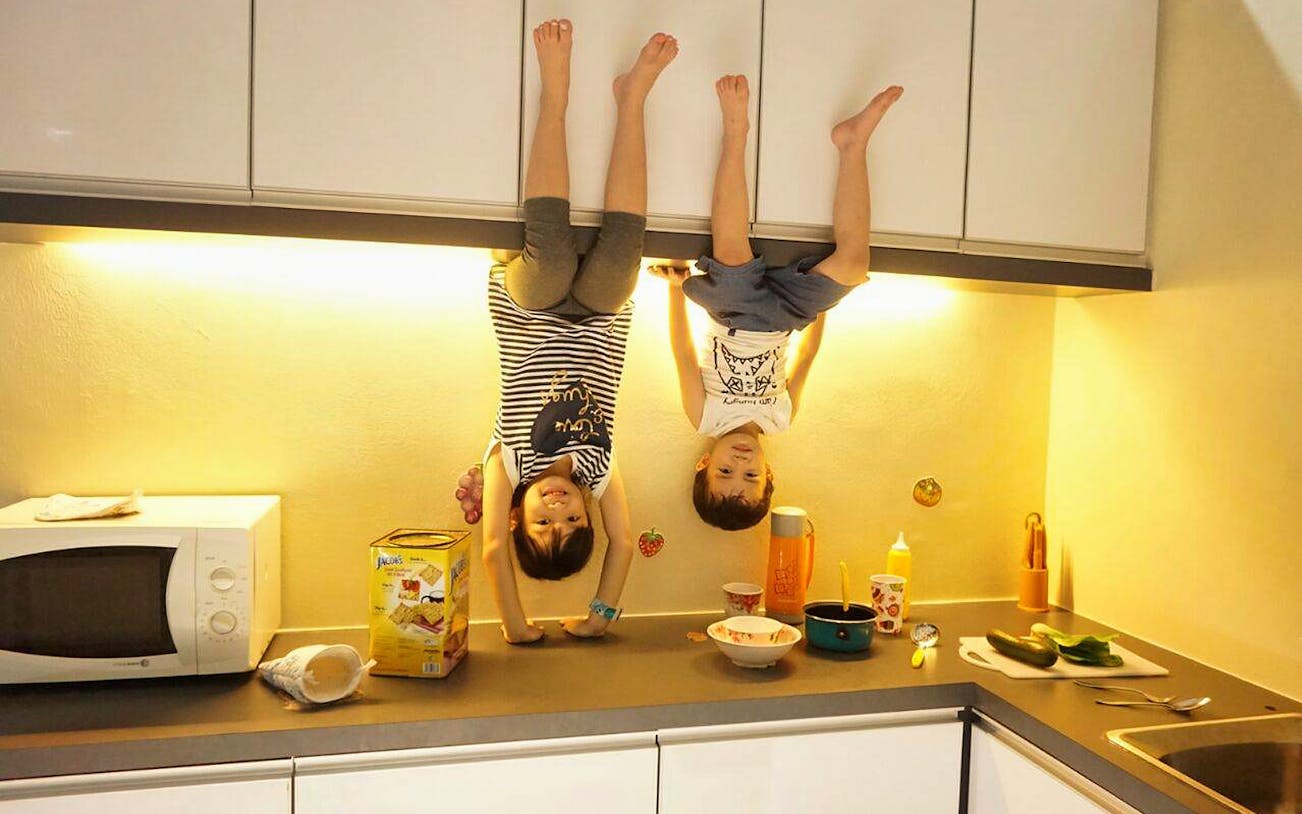 Children appearing upside down in a kitchen at Upside Down House Melaka.