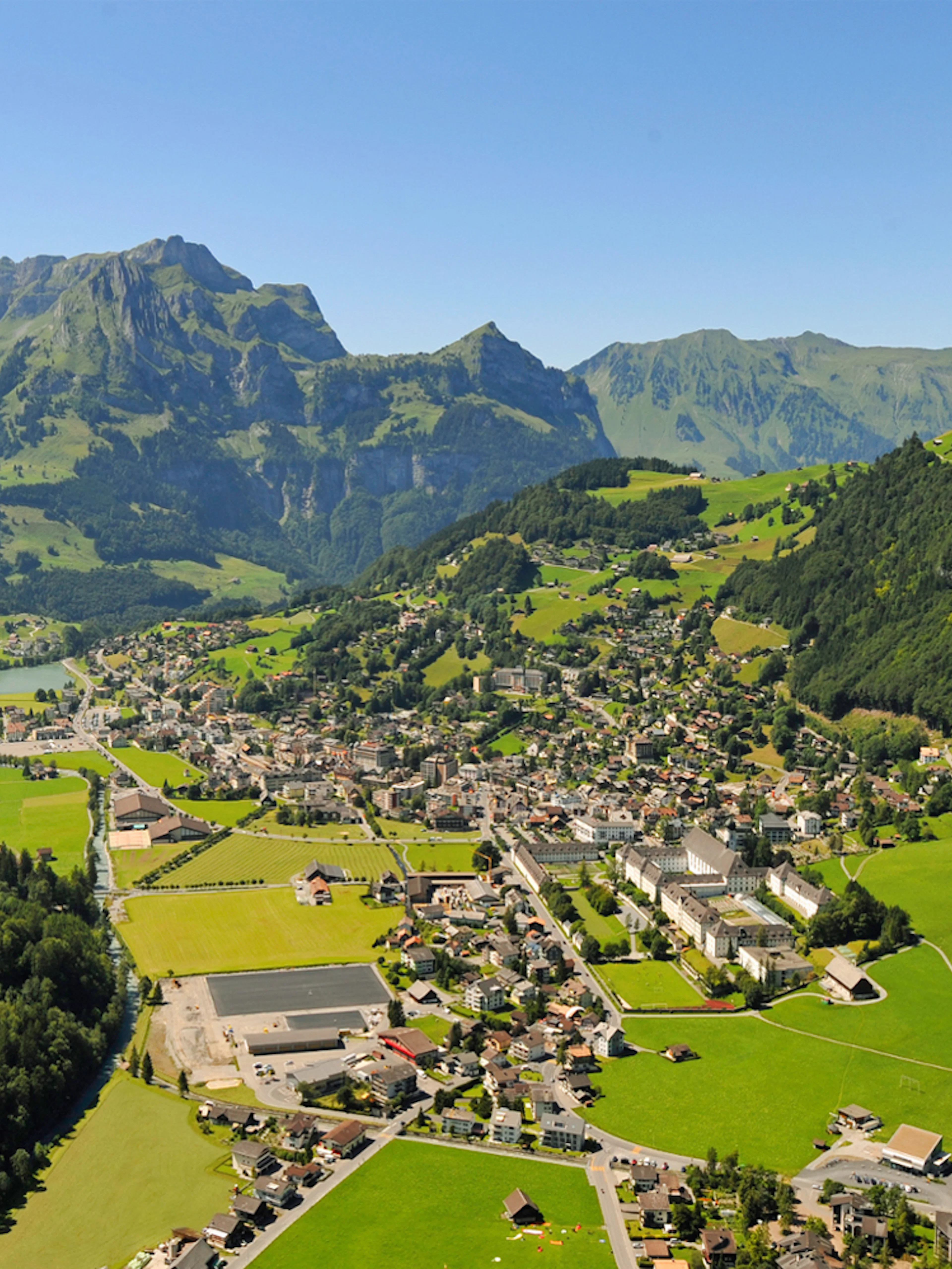 Aerial view of Engelberg, a typical Alpine village surrounded by mountains and greenery.