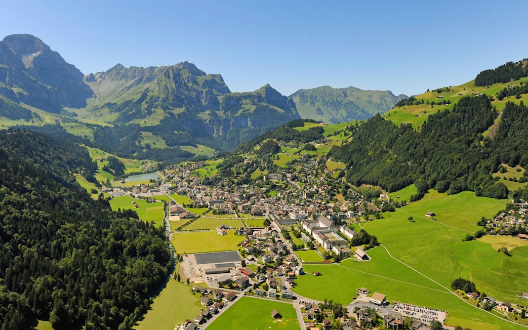 Aerial view of Engelberg, a typical Alpine village surrounded by mountains and greenery.