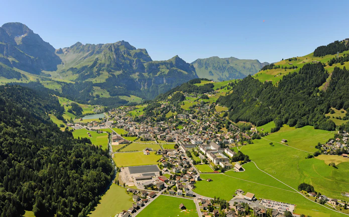 Aerial view of Engelberg, a typical Alpine village surrounded by mountains and greenery.