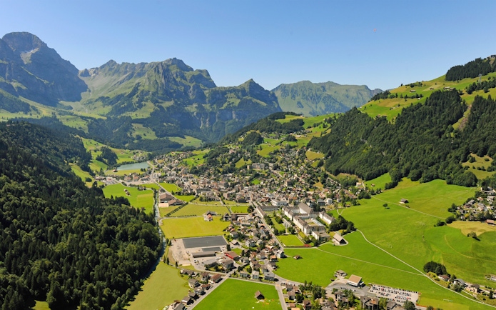 Aerial view of Engelberg, a typical Alpine village surrounded by mountains and greenery.