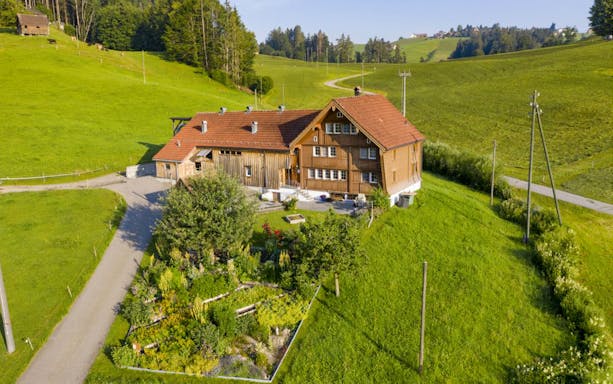 Appenzell countryside farmhouse surrounded by green hills on a full-day tour from Zürich.