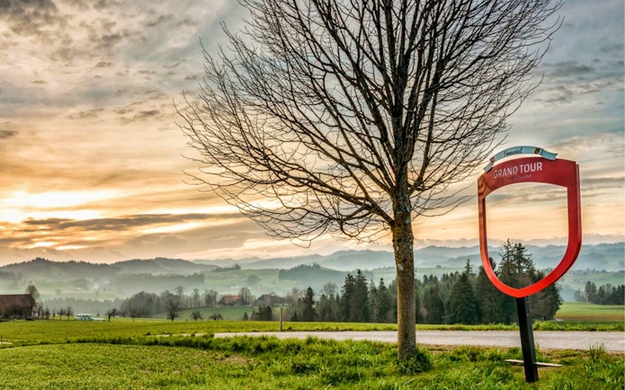 Grand Tour sign and tree with Emmental landscape near Bern, Switzerland.