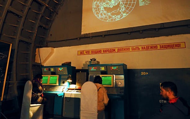 Visitors at control panels inside Bunker 42 Cold War Museum during guided tour.