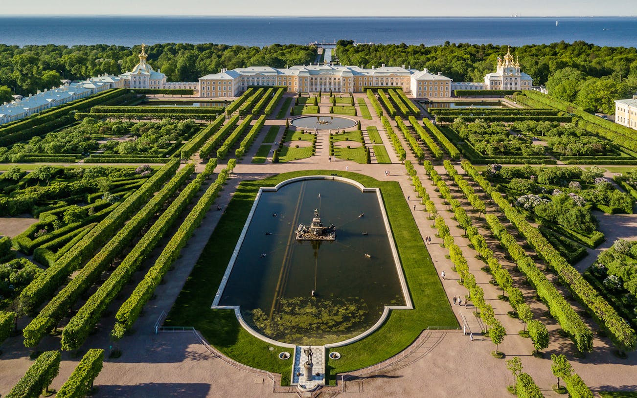 Aerial view of Peterhof Grand Palace and Gardens, featuring symmetrical pathways and a central fountain.
