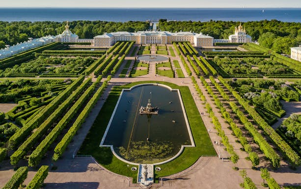 Aerial view of Peterhof Grand Palace and Gardens, featuring symmetrical pathways and a central fountain.