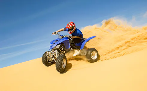 Quad biking on sand dunes during a desert safari adventure.