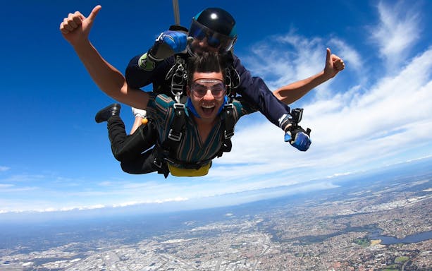 Tandem skydivers over Perth cityscape at 14,000 feet.