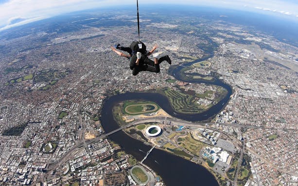 Skydiver over Perth cityscape with Swan River visible below.