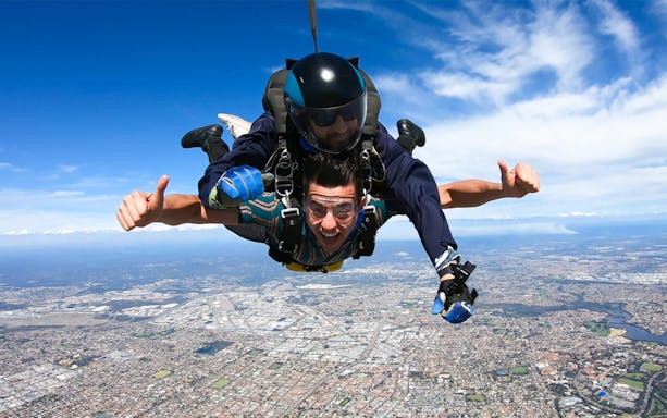 Tandem skydivers over Perth cityscape at 14,000 feet.