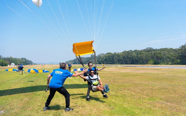 Tandem skydivers landing in Hunter Valley with parachute assistance.