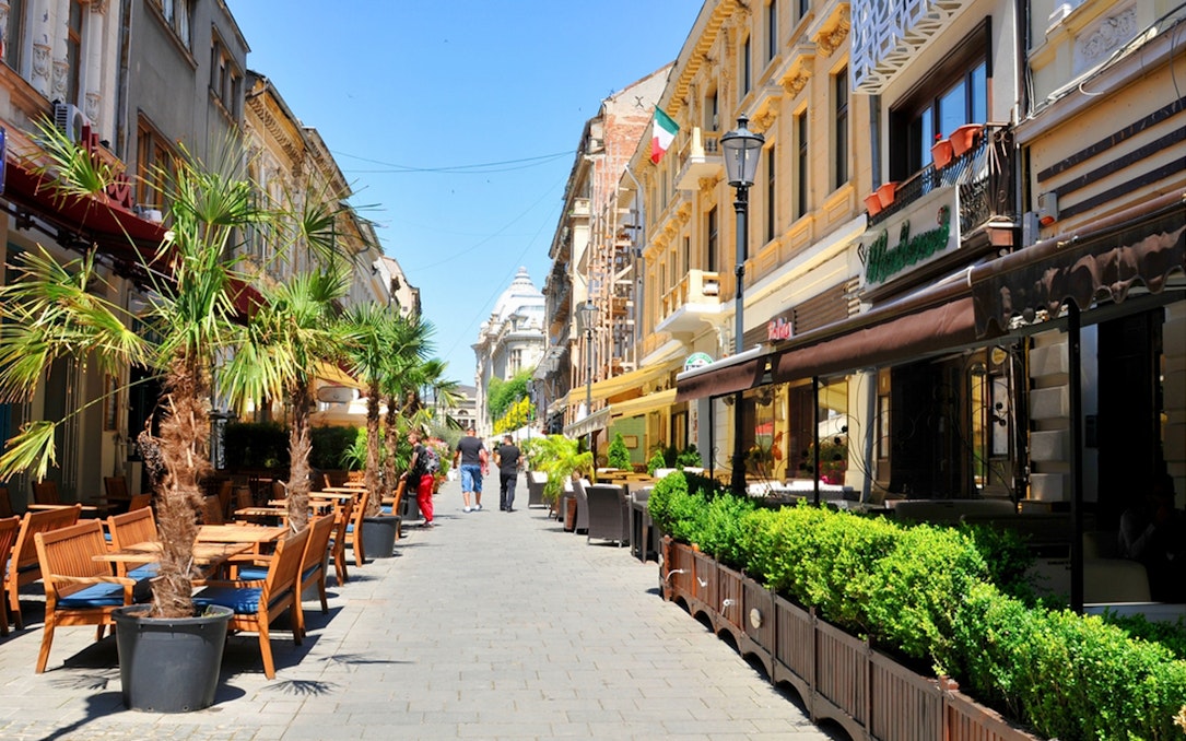 Street cafes and historic buildings in Old Town Bucharest during a walking food tour.