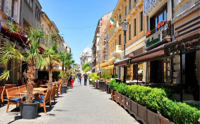 Street cafes and historic buildings in Old Town Bucharest during a walking food tour.