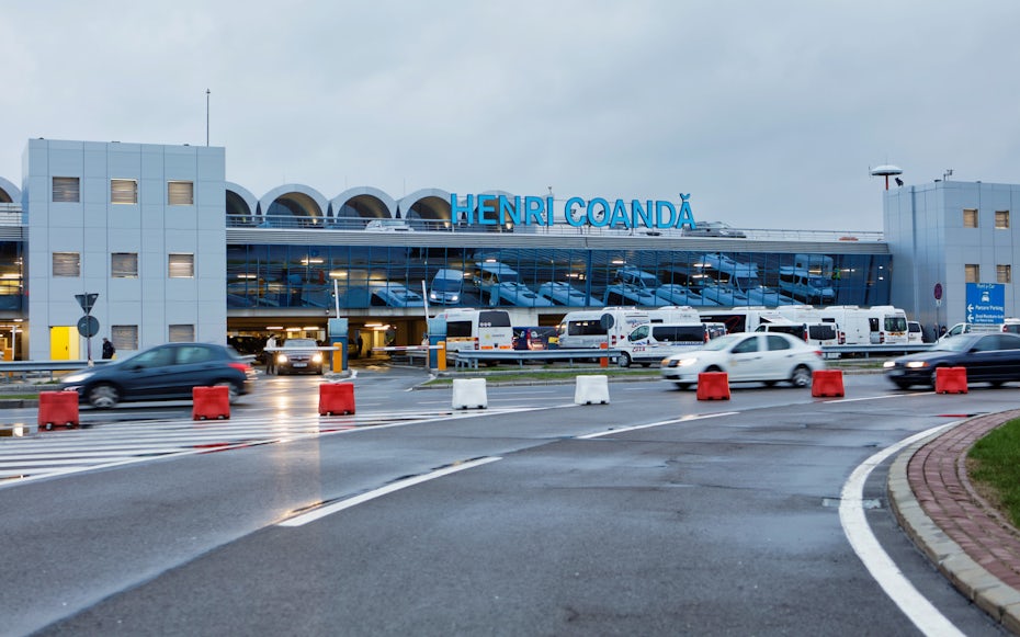 Henri Coandă Airport exterior with cars and buses in Bucharest.