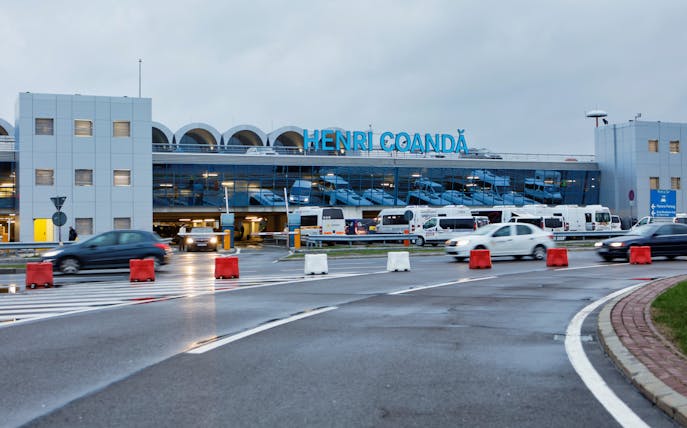 Henri Coandă Airport exterior with cars and buses in Bucharest.