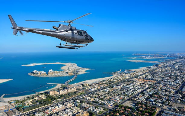 Helicopter over Dubai coastline with aerial view of The Palm Jumeirah.