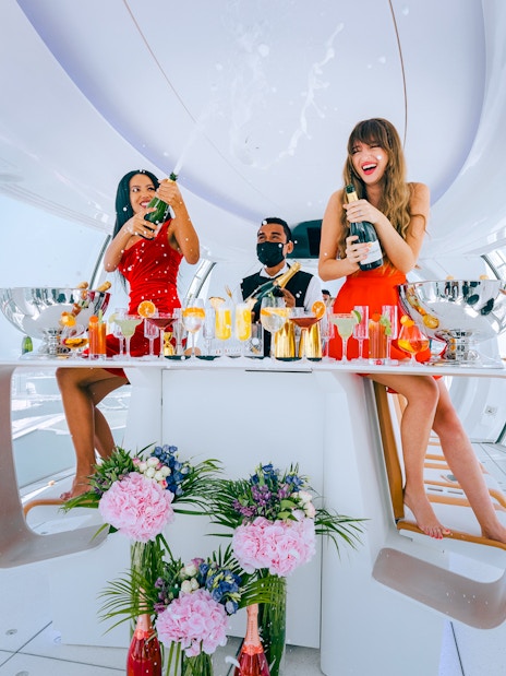 Guests enjoying drinks inside Ain Dubai cabin with city views.