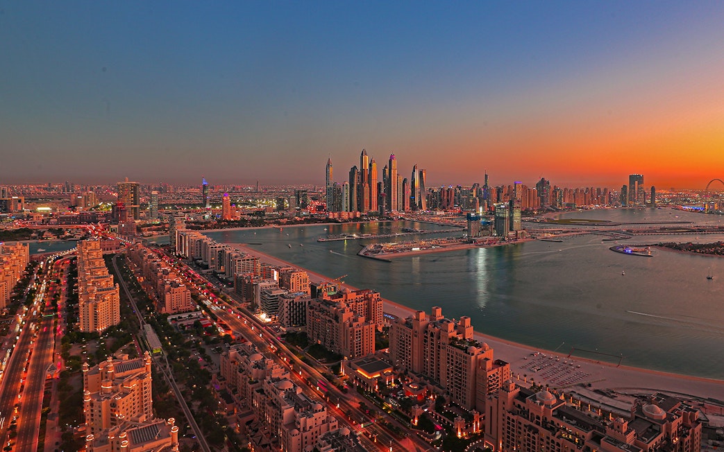 Dubai skyline at sunset with Palm Jumeirah and skyscrapers in view.