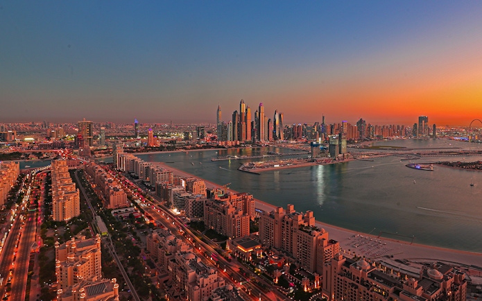 Dubai skyline at sunset with Palm Jumeirah and skyscrapers in view.
