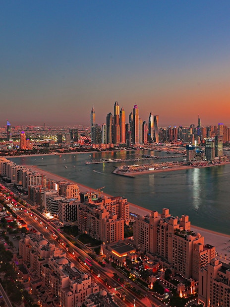 Dubai skyline at sunset with Palm Jumeirah and skyscrapers in view.