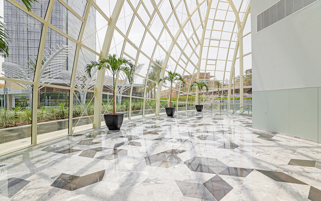Modern glass atrium with palm trees at Dubai Frame, showcasing city views.