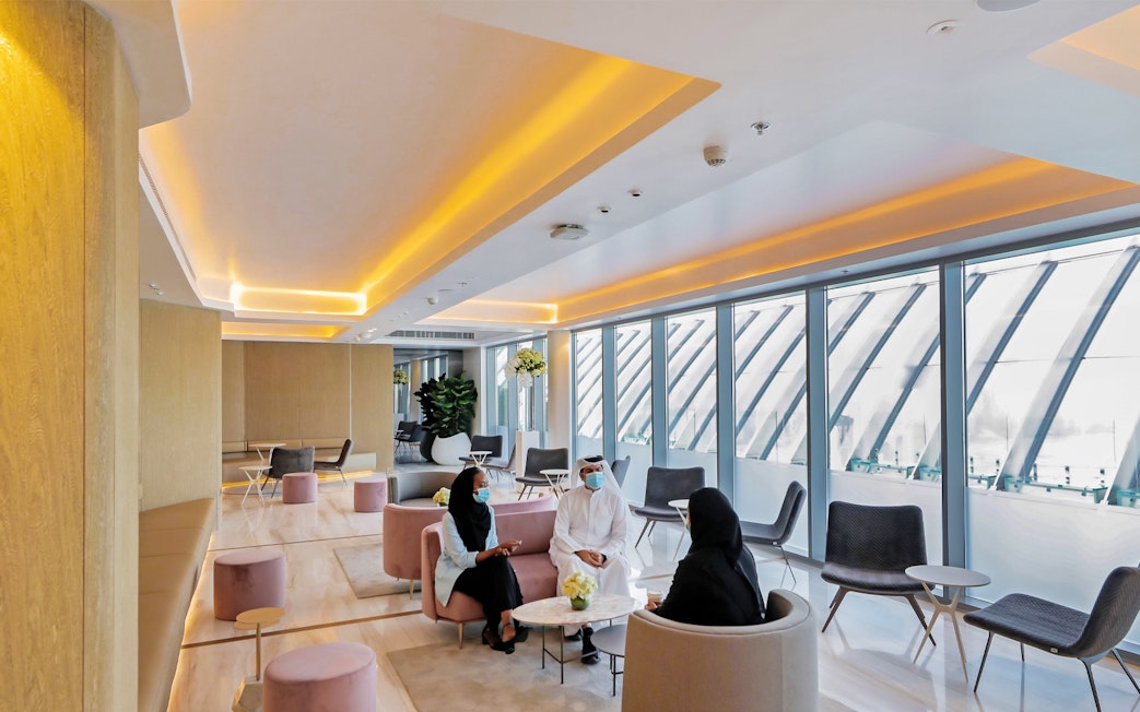 Modern lounge area at The View At The Palm, Dubai, with people seated and large windows.