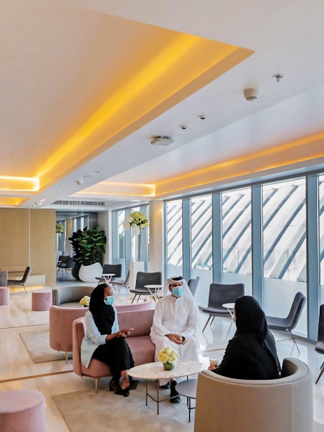 Modern lounge area at The View At The Palm, Dubai, with people seated and large windows.