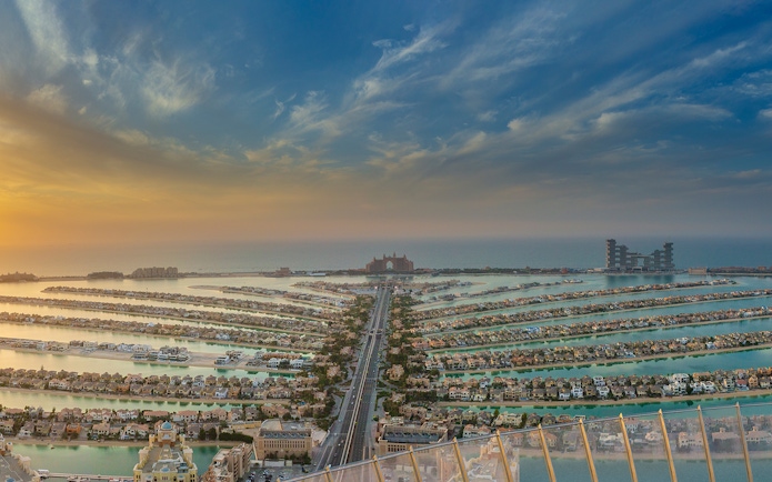 Aerial view of Palm Jumeirah in Dubai at sunset, featuring Atlantis The Palm hotel.