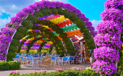 Colorful umbrella archway at Dubai Miracle Garden with visitors seated below.