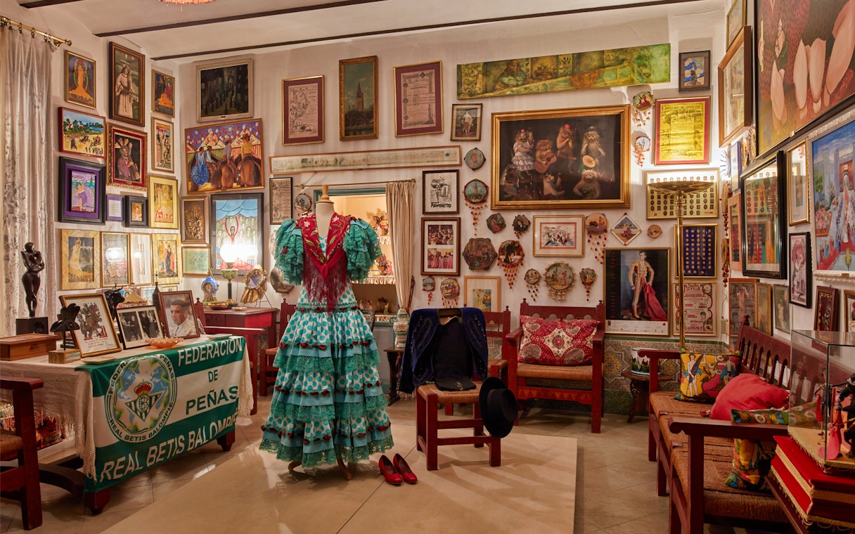 Flamenco dress display in art-filled room at Palacio de las Dueñas, Seville.