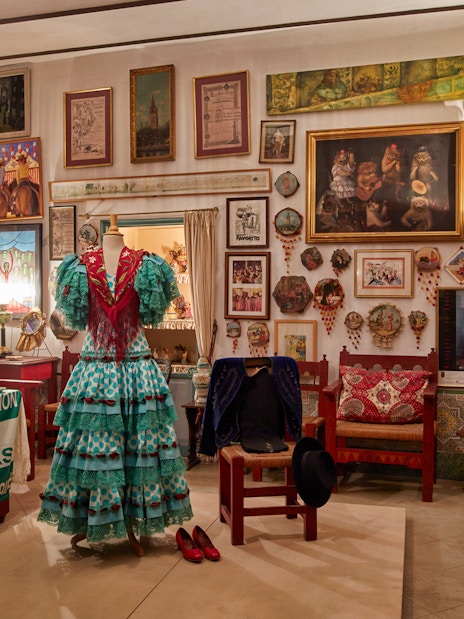 Flamenco dress display in art-filled room at Palacio de las Dueñas, Seville.