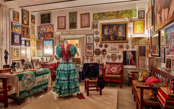 Flamenco dress display in art-filled room at Palacio de las Dueñas, Seville.