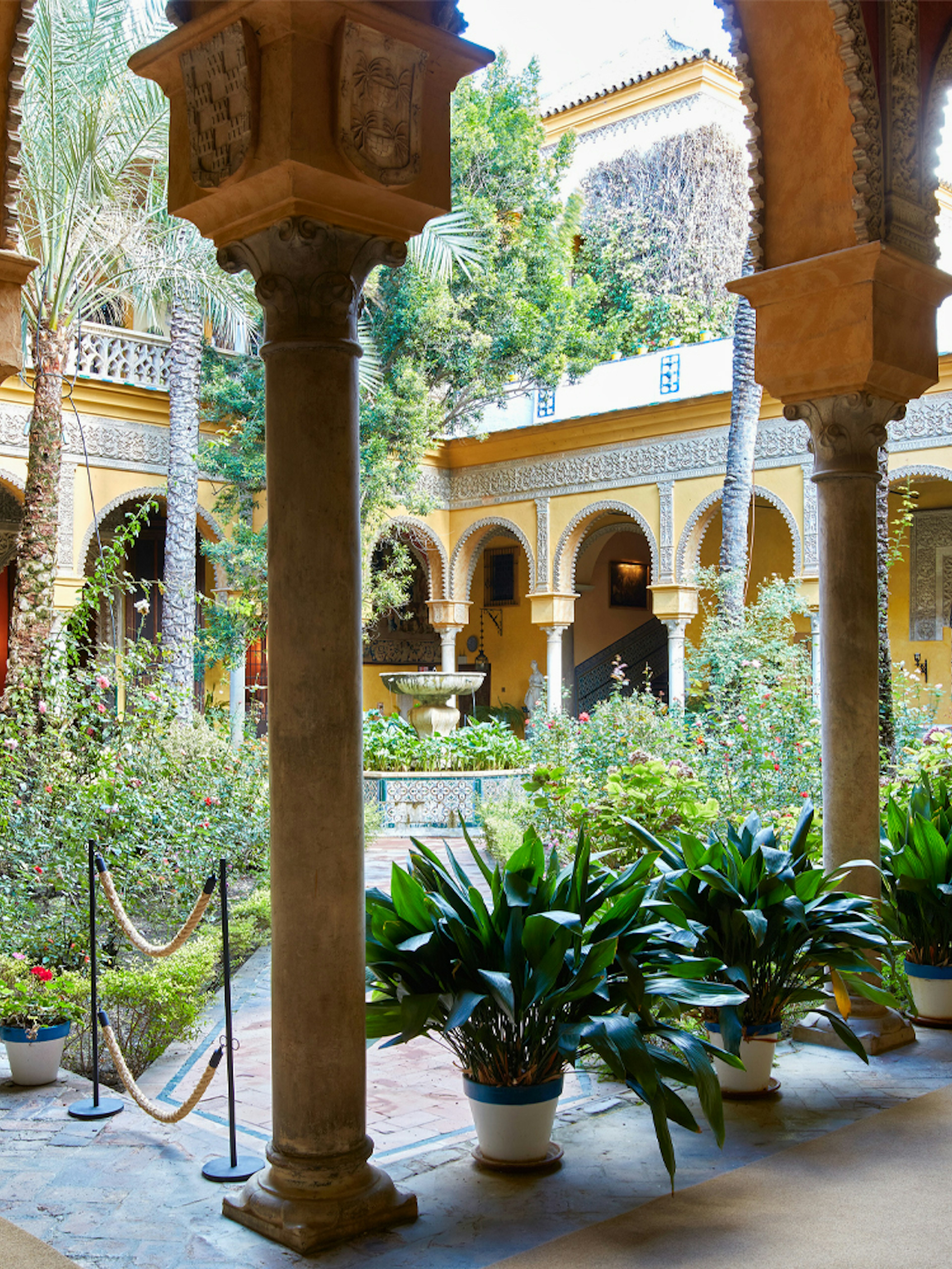 Palacio de las Dueñas courtyard with arches and lush garden in Seville.