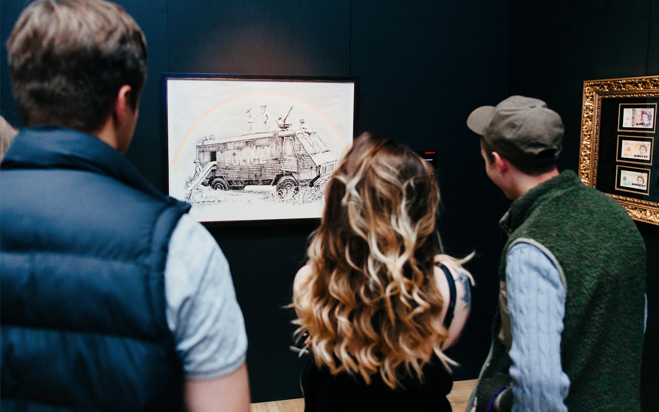 Visitors viewing Banksy artwork at an exhibition.