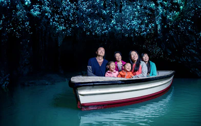 Group enjoying boat tour under glowworms in Waitomo Caves, New Zealand.
