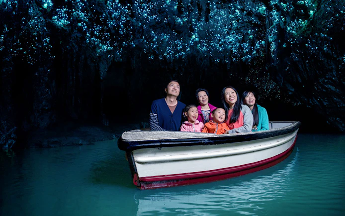 Group enjoying boat tour under glowworms in Waitomo Caves, New Zealand.