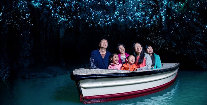 Group enjoying boat tour under glowworms in Waitomo Caves, New Zealand.